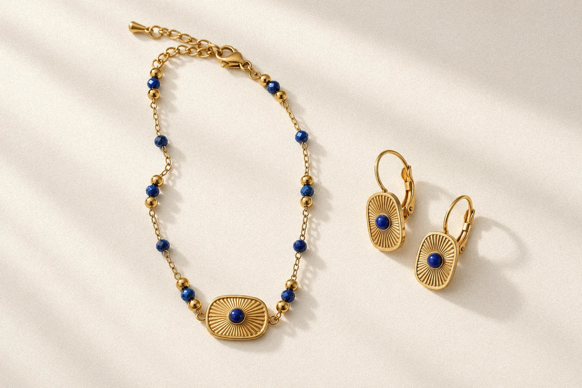 Aurora Talisman Bracelet and a pair of blue-centered Aurora earrings arranged separately on an ivory tabletop.