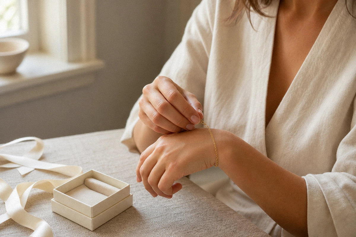 Woman fastening a delicate gold bracelet on her wrist beside an open jewelry box