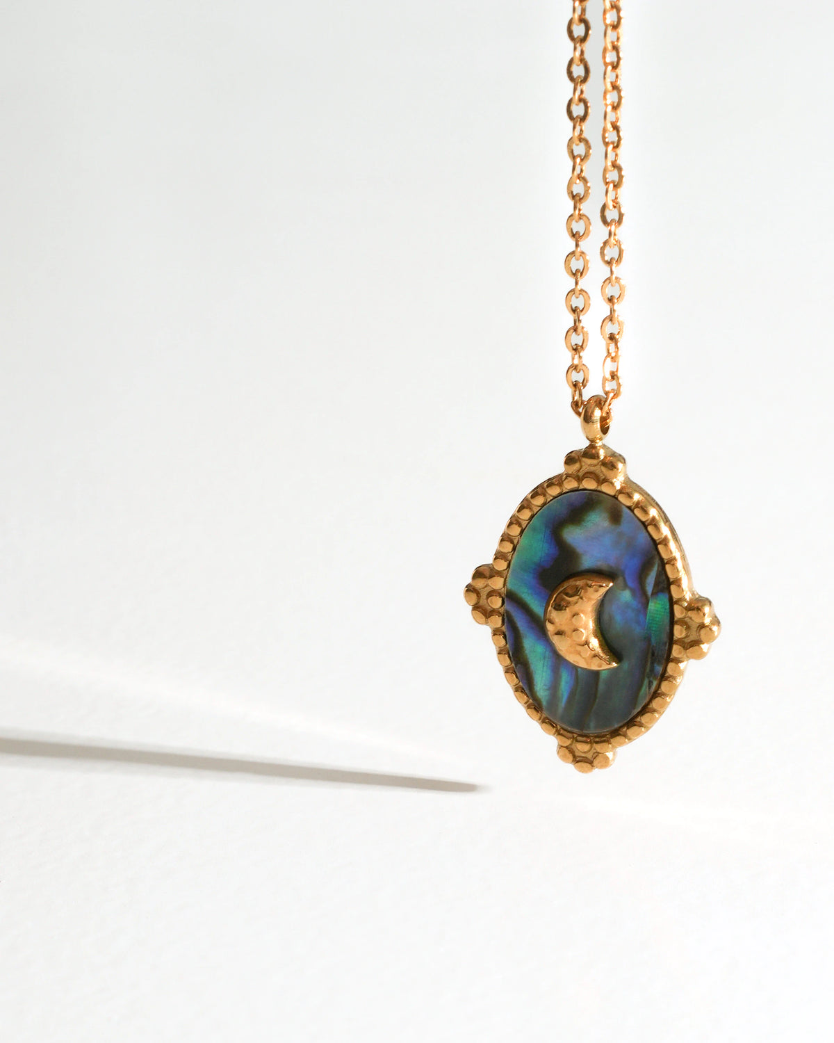 Close-up of Tidal Stone Pendant Necklace with a crescent moon on iridescent shell