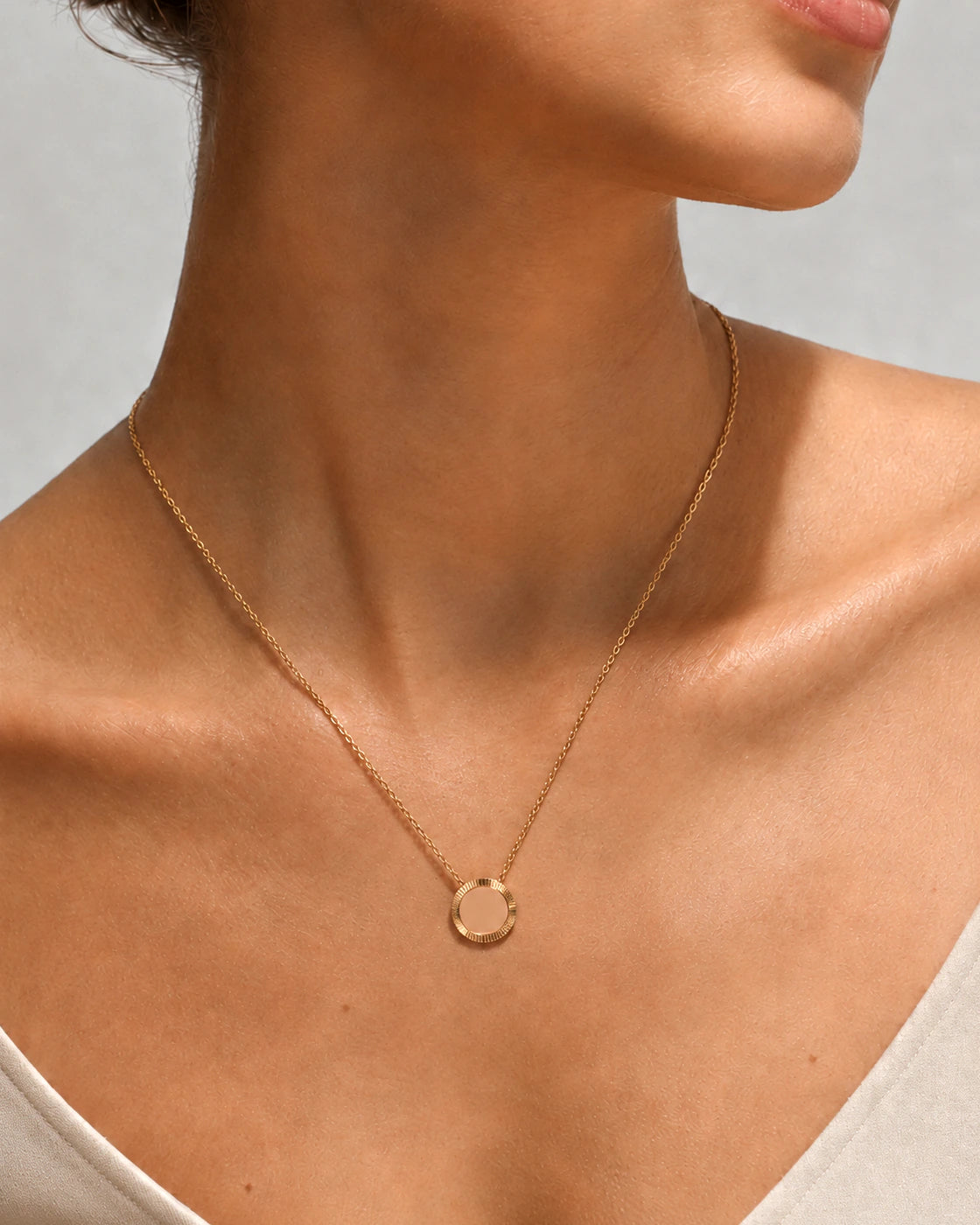 Studio close-up of a model wearing the Gold Reflection Pendant Necklace