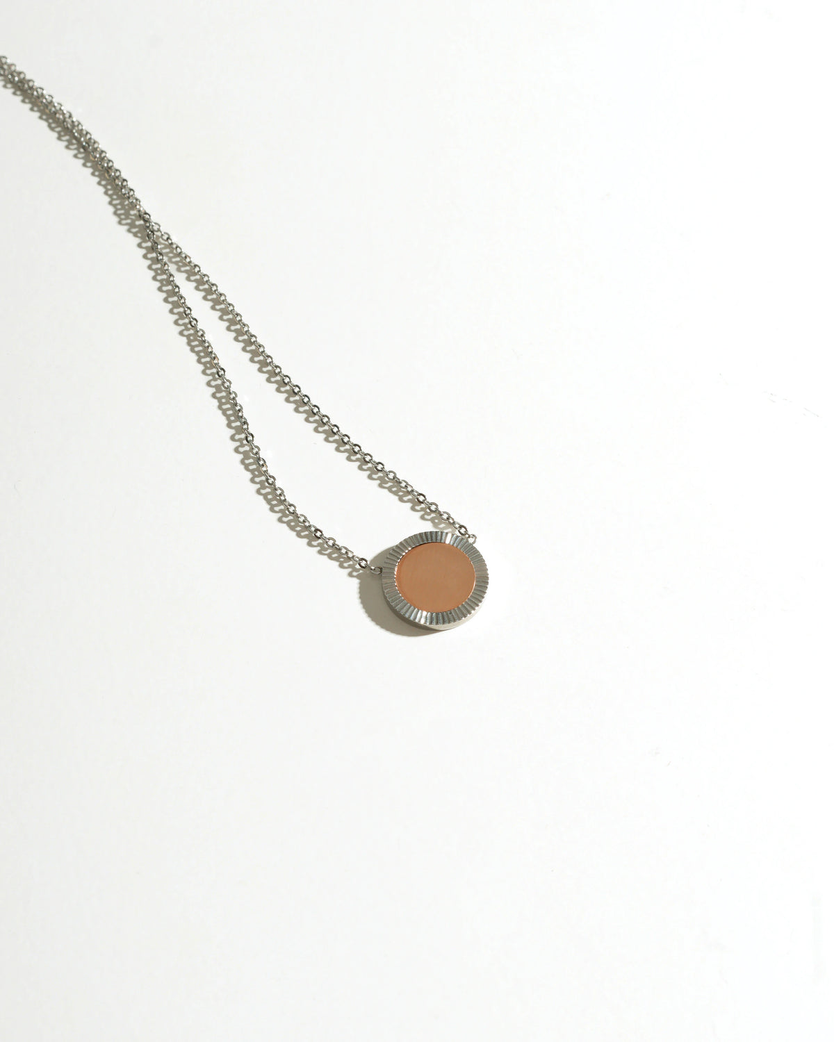 Silver Reflection Pendant Necklace lying on white surface with circular mirror pendant
