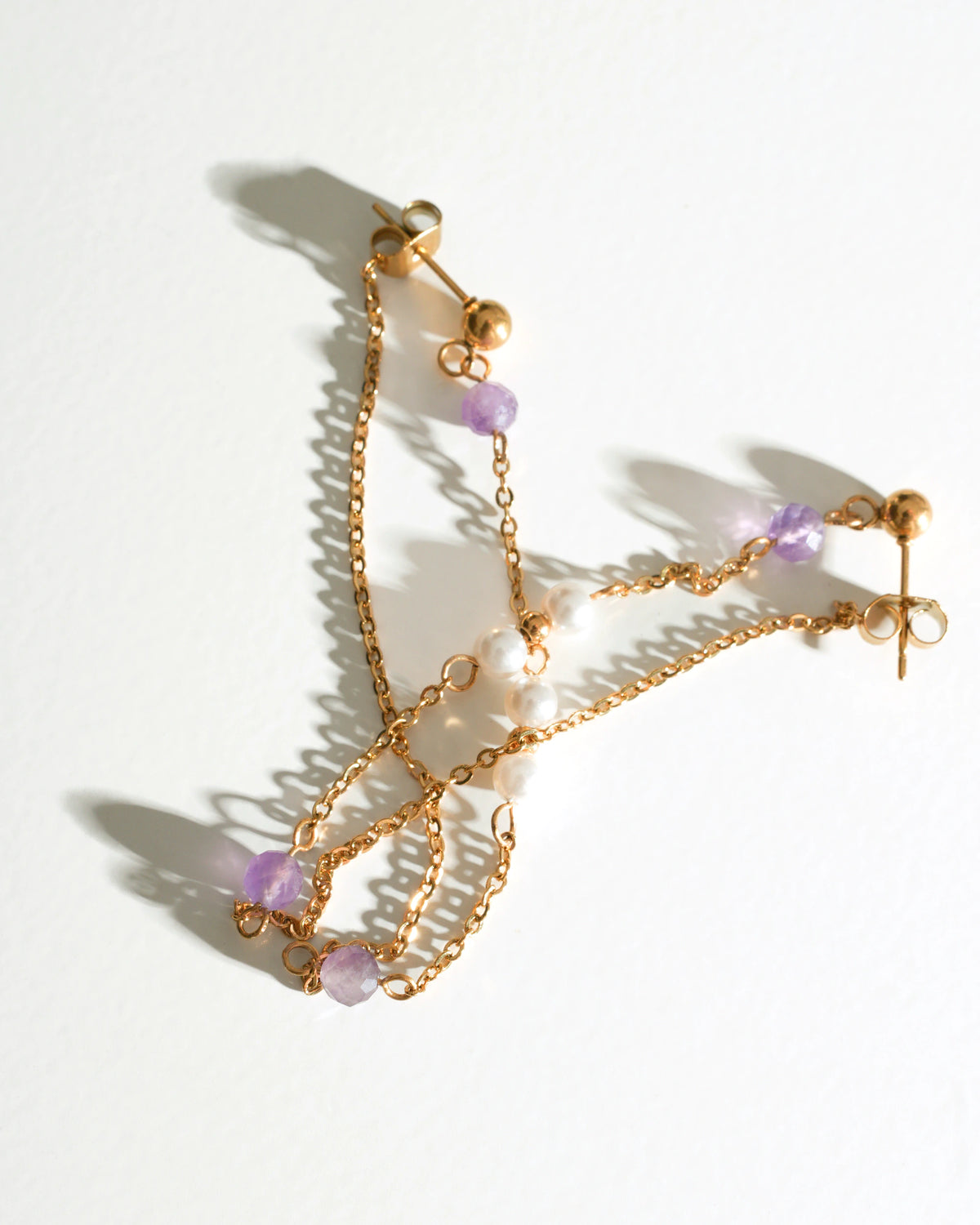 Pair of Lavender Drift Drop Earrings laid flat in warm sunlight