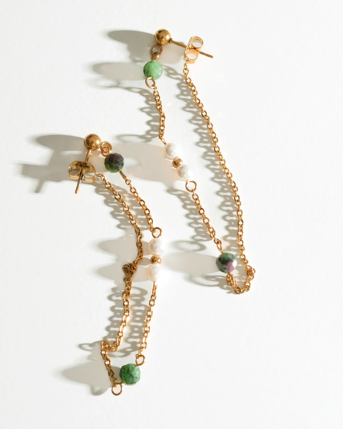 Pair of Solstice Drift Drop Earrings laid flat with long gold chains