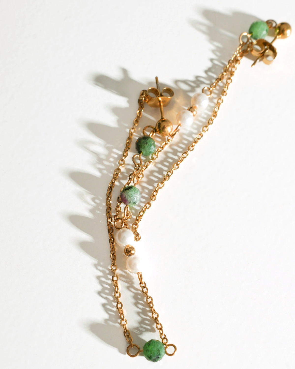 Solstice Drift Drop Earrings with green stones and pearl beads laid flat
