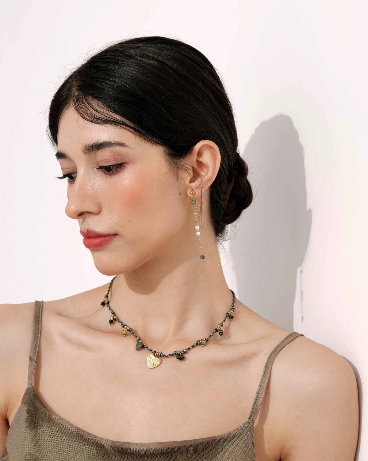 Model wearing the Solstice Drift Drop Earrings with a green bead necklace