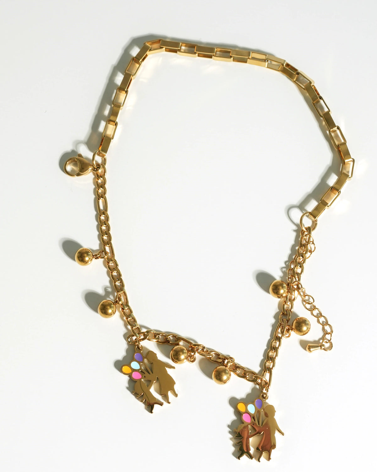 Gold charm bracelet featuring mother and child silhouettes with colorful enamel balloons and gold bead accents.