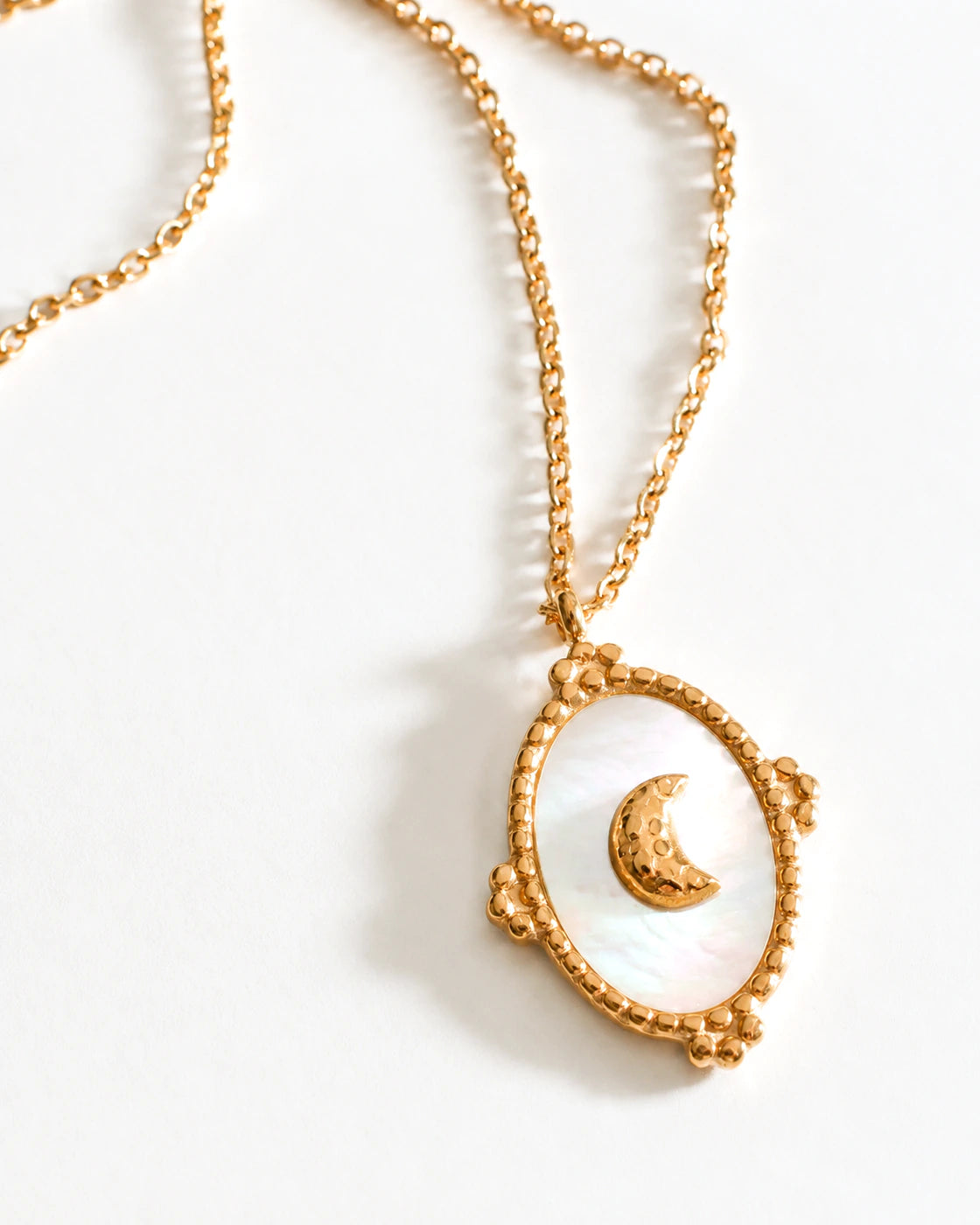 Close-up of Tide Stone Pendant Necklace with a crescent moon on white mother-of-pearl