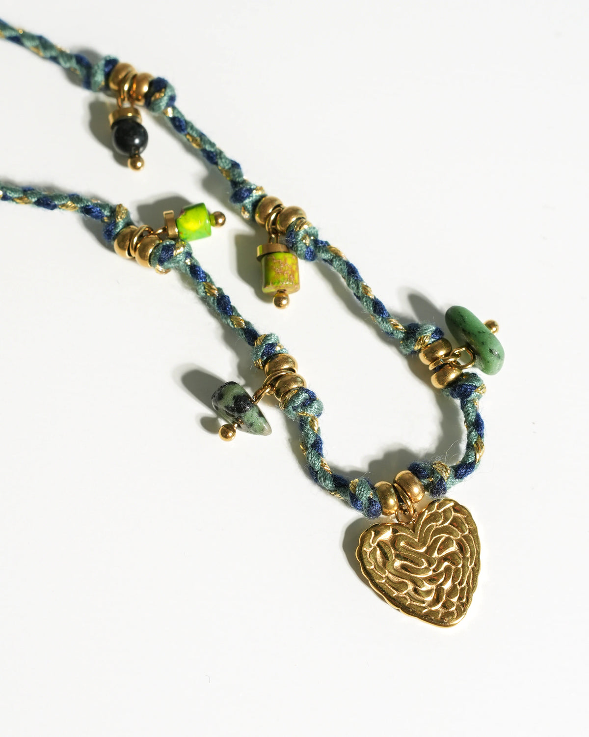 Close-up of Verdant Amity Necklace with braided cord, green stones and gold heart pendant