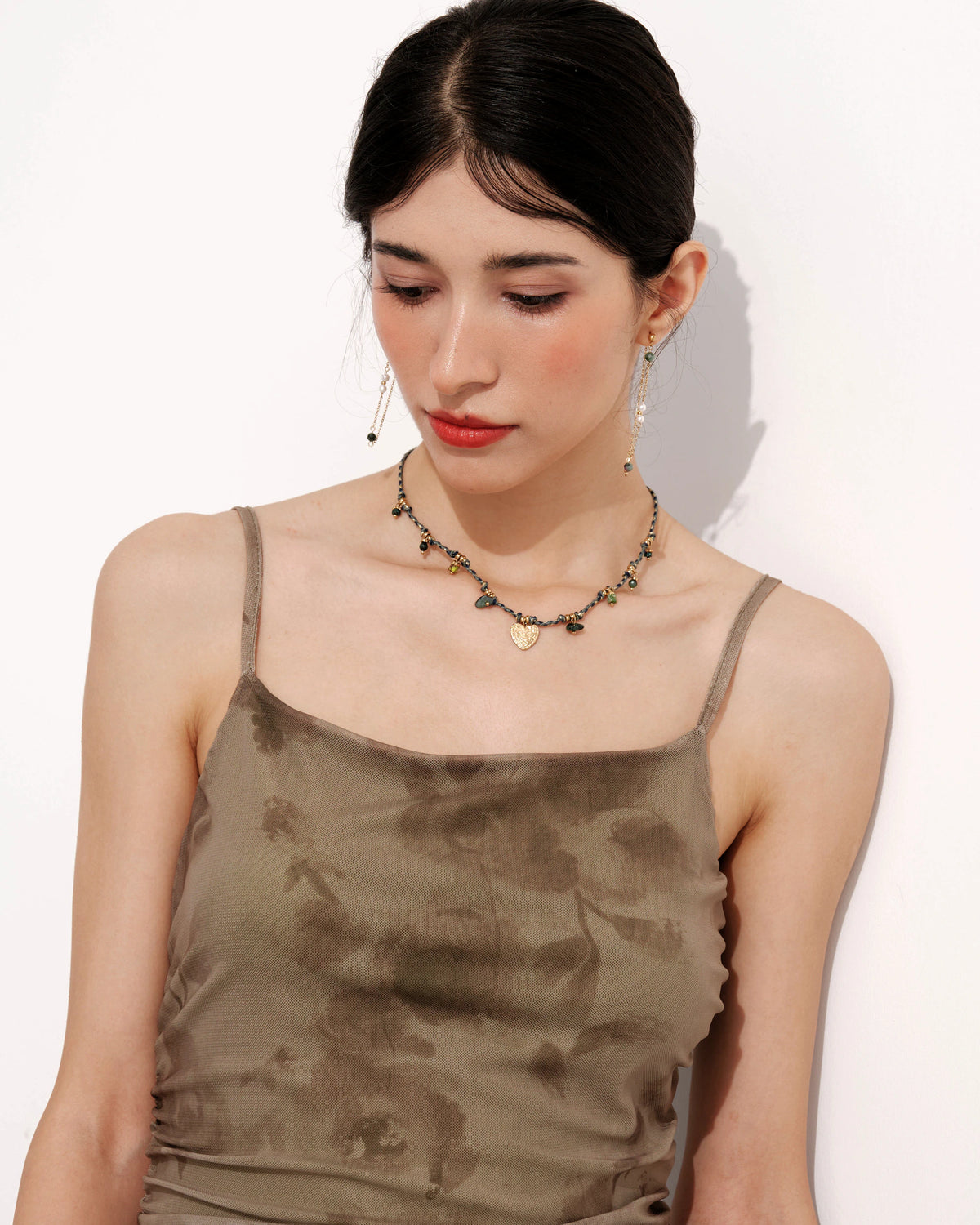 Verdant Amity Necklace with green beads and a gold heart pendant laid flat