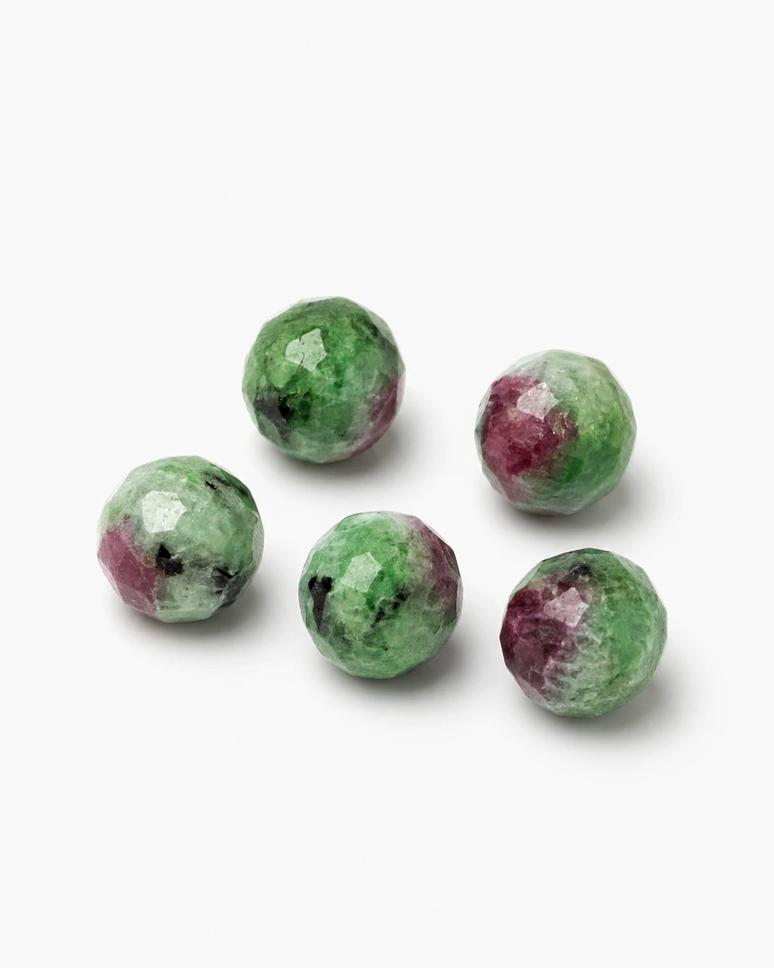 Polished ruby zoisite stones on a white background