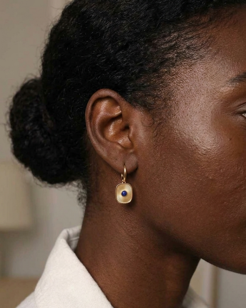 Close-up of model wearing gold sunburst leverback earring with lapis lazuli