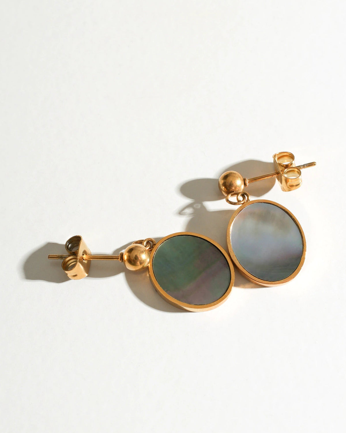Mist Tide Stud Earrings with grey mother-of-pearl discs on a cream background